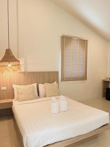 a bedroom with a large white bed with two towels at LAIWAII HOME in Hat Yai