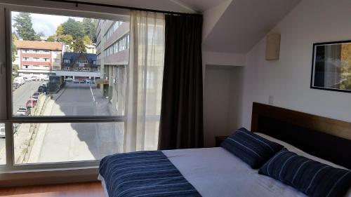sypialnia z łóżkiem i dużym oknem w obiekcie Centro Cívico departamentos w mieście Bariloche