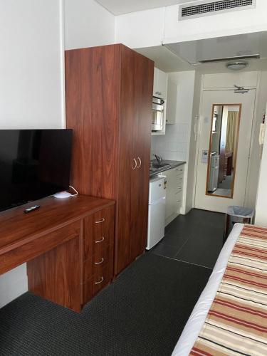 a bedroom with a large wooden cabinet and a kitchen at By the Harbour Gem in Sydney
