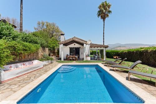 a swimming pool with chairs and a house at Villa Caty in Jimena de la Frontera