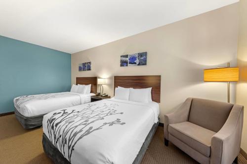 a hotel room with two beds and a chair at Sleep Inn & Suites Norman near University in Norman