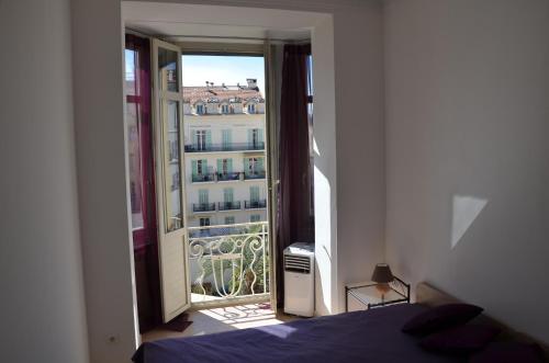 - une chambre avec un lit et une porte ouverte sur un balcon dans l'établissement C027-Spacieux & Lumineux appartement - Centre de Cannes, à Cannes
