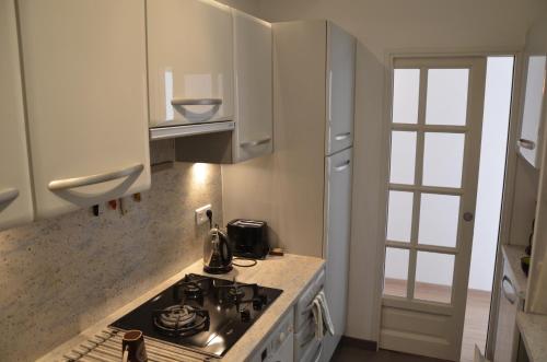 une cuisine avec des armoires blanches et un four à plaques de cuisson dans l'établissement C027-Spacieux & Lumineux appartement - Centre de Cannes, à Cannes