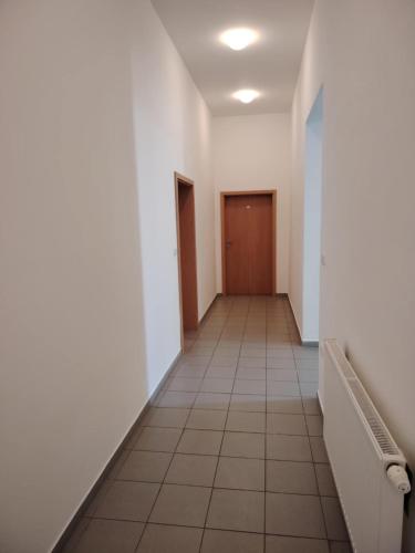 an empty hallway with white walls and a brown door at Penzion Zamecek in Uherčice