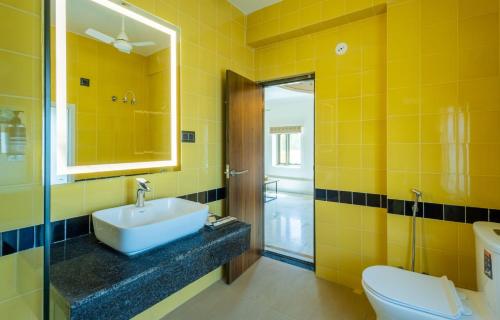 een gele badkamer met een wastafel en een toilet bij Zone Connect by The Park Jaisalmer in Jaisalmer