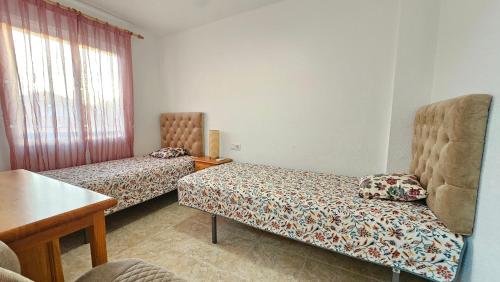 Habitación con 2 camas, silla y mesa. en Cozy apartment beach 300 metros, en Santa Pola