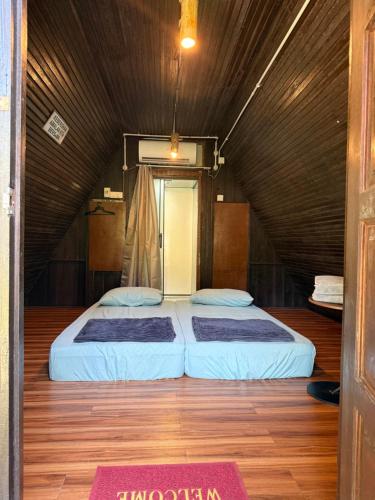 two beds in a room with a wooden floor at Chalet Kuala Woh Resort in Tapah