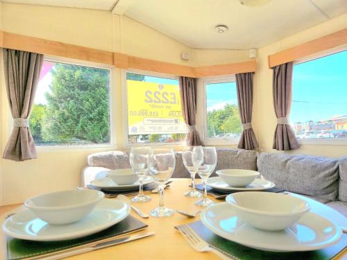 a dining room table with plates and wine glasses at Cherry, 2 Bed, 6 Berth With Electric Panel Heaters 70724C in Great Yarmouth