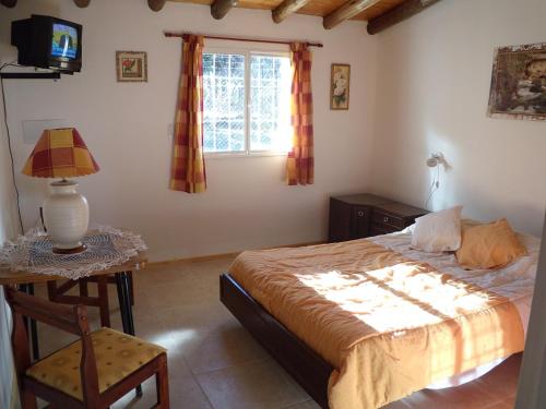a bedroom with a bed and a table and a window at Cabañas Del Sol in Las Compuertas