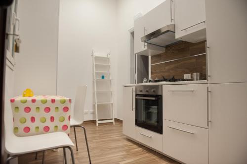 una cucina con armadi bianchi, tavolo e sedia di campo appartamenti a Trapani