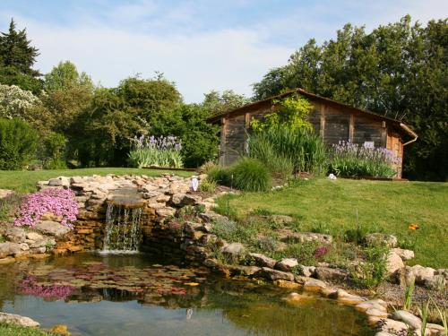 a pond in a garden with a stone wall at Couleur Lavande in Le Thor