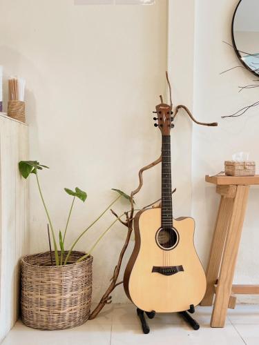 a guitar leaning against a wall next to a plant at LAIWAII HOME in Hat Yai