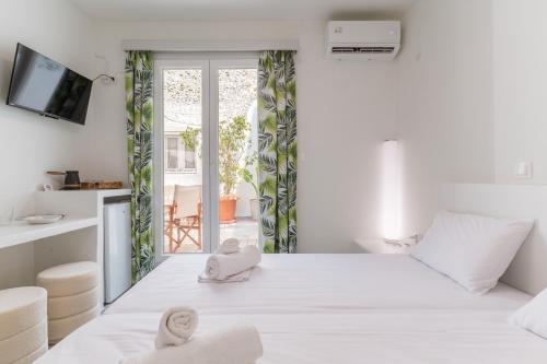 Un dormitorio blanco con una cama grande con toallas. en A Tinian Room 3, en Tinos