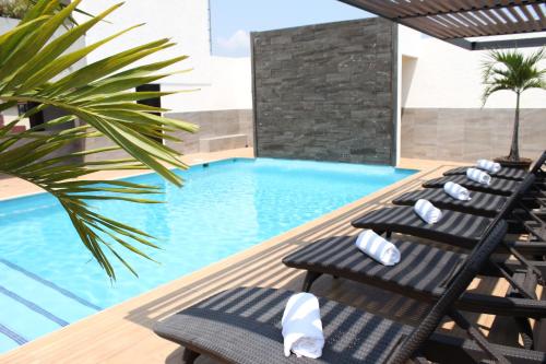 una piscina con tumbonas y una palmera en Hotel Mesón de la Chinantla, en San Juan Bautista Tuxtepec