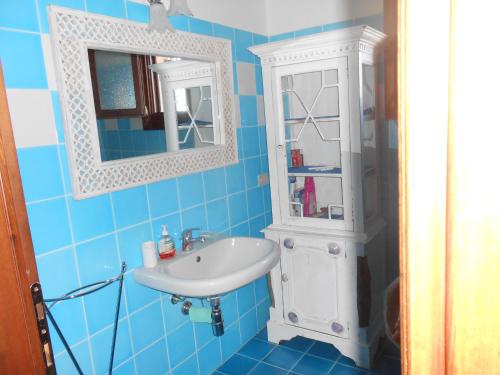 een blauwe badkamer met een wastafel en een medicijnkastje bij Villino Caddu in San Teodoro