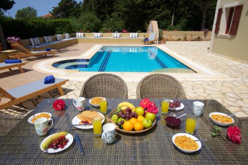a table with a tray of food and fruit next to a pool at Villa Emily in Fiskardho