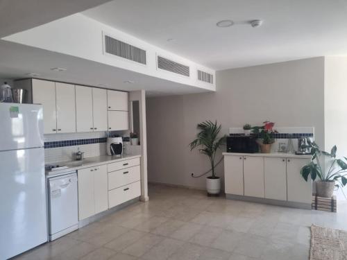 a kitchen with white cabinets and a white refrigerator at אוקיינוס במרינה הרצליה פיתוח in Herzliyya B
