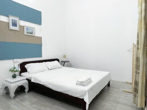 a bedroom with a large white bed and a blue wall at Hoe Stay - Where to stay in Hanoi