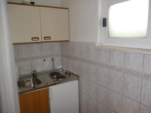 a small kitchen with a sink and a mirror at Studio Apartman Mira in Neum