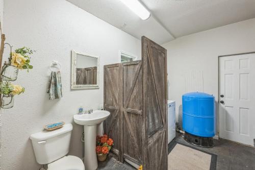 a bathroom with a wooden door and a toilet and a sink at Hill Country Getaway Near San Marcos River home in San Marcos