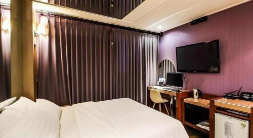 a hotel room with a bed and a desk with a computer at Seven Motel Ansan in Ansan