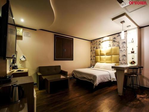 a bedroom with a bed and a chair and a desk at Seven Motel Ansan in Ansan