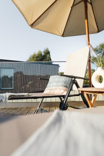 a chair sitting on a deck with an umbrella at Lieblingsplatz Parey - Ferienhaus am See in Parey