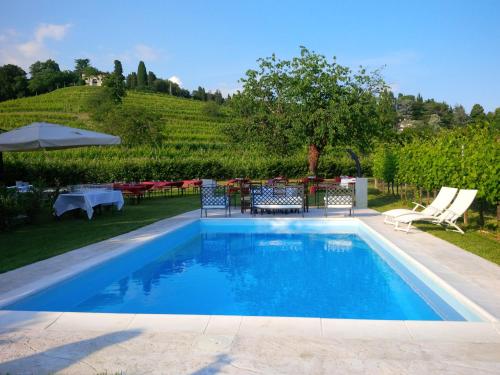 una piscina con sedie, tavolo e ombrellone di Agriturismo Giorgio Colutta a Manzano