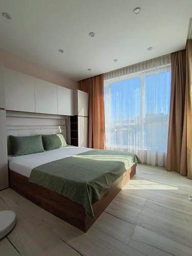 a bedroom with a large bed and a large window at Boutique apartment green 2 in Plovdiv