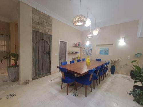 a dining room with a wooden table and blue chairs at Riad d'exception vue mer au coeur de la médina Essaouira - Mandji Dream in Essaouira