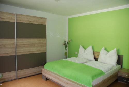 a green bedroom with a bed with white pillows at Ferienwohnung Kendler in Hüttschlag