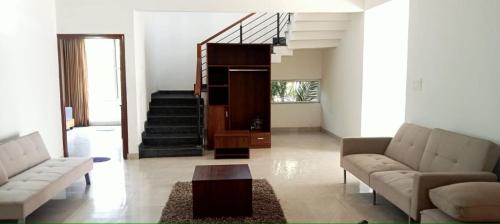 a living room with two couches and a staircase at PUSHPAM RANCHES And RESORT in Mattigiri