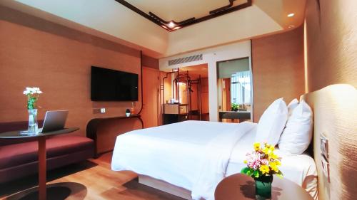 a hotel room with a bed and a couch and a television at Mercure Surabaya Grand Mirama in Surabaya