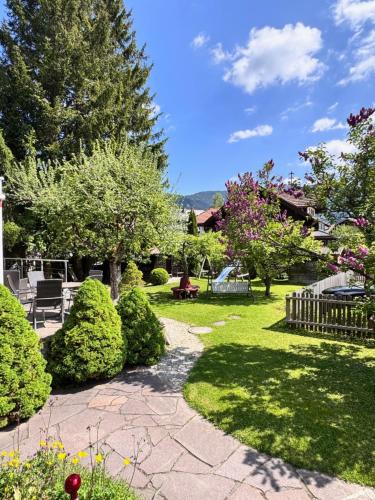 a garden with bushes and trees and a walkway at Hotel Garni Otto Huber in Oberammergau