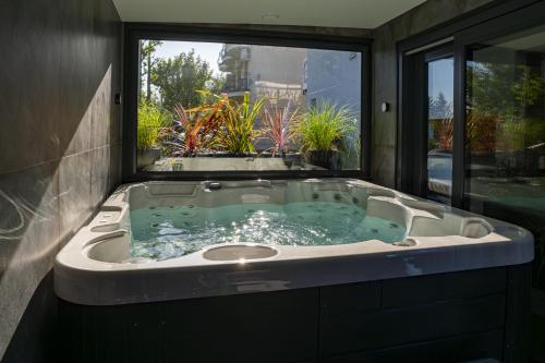 a large bath tub in a room with a window at Apartamenty BLUE BALTIC SPA Jacuzzi & Sauna MORZE in Chłopy