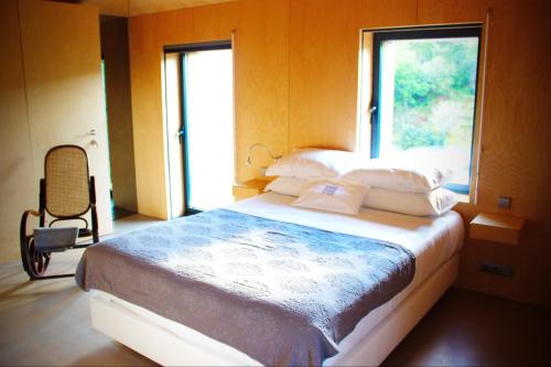 a bedroom with a bed with a window and a chair at Melgaço Alvarinho Houses in Melgaço