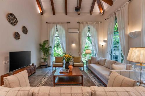 a living room with a couch and a tv at Villa Lluvia 5bhk-Huge Pvt Pool-Caretaker-Bathtub-Big Garden-Genset Backup- Siolim in Oxel