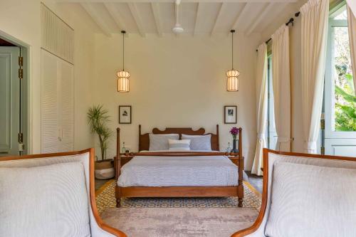 a bedroom with a bed and two chairs at Villa Lluvia 5bhk-Huge Pvt Pool-Caretaker-Bathtub-Big Garden-Genset Backup- Siolim in Oxel
