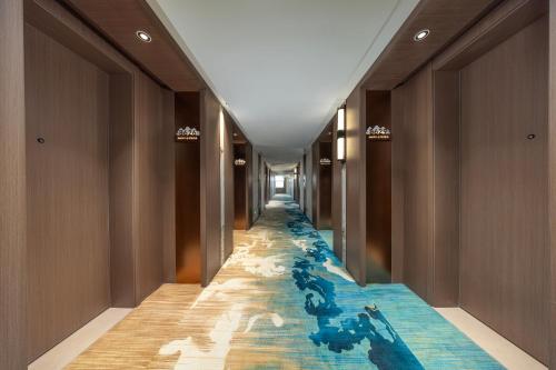 a corridor of a hotel with a blue tile floor at Mingzhi Shangchun Holiday Hotel in Dujiangyan