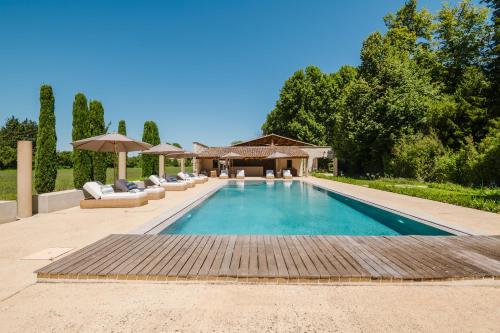 a pool with chairs and umbrellas in a yard at Château Saint Perret in Avignon