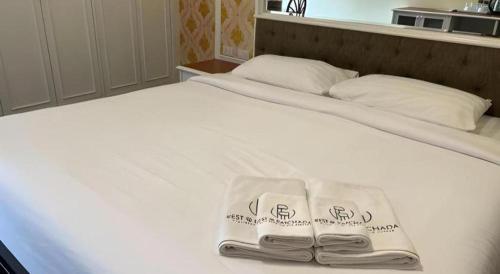 a white bed with two towels on top of it at Rest@Ratchada hotel in Bangkok
