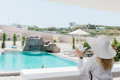 a woman in a white hat looking at a swimming pool at Santoterra Antigua Suites in Karterados