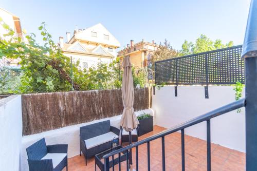 a patio with chairs and an umbrella and a fence at Pyrenees Escape with Terrace and BBQ in Sabiñánigo
