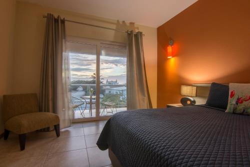a bedroom with a bed and a window with a balcony at Costa Esmeralda Village in Palm-Eagle Beach