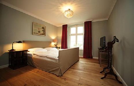 Schlafzimmer mit einem Bett und einem Fenster mit roten Vorhängen in der Unterkunft Jadgschloss zu Hohen Niendorf in Hohen Niendorf