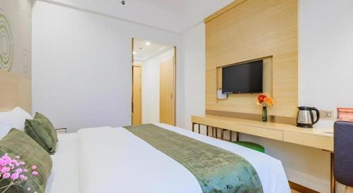 a bedroom with a bed and a desk with a tv at GreenTree Inn Shanghai Jingan Railway Station Xinzha Road Business Hotel in Shanghai