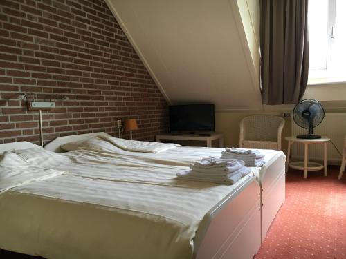 a bedroom with a white bed with a brick wall at Recreatiecentrum de Kluft in Ossenzijl