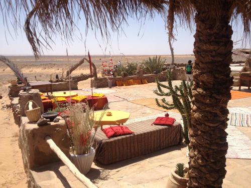a desert with two beds and a palm tree at Maison Boutchrafine in Erfoud