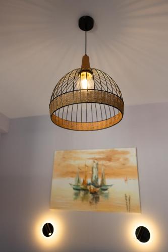 aendant light hanging from a ceiling with a painting at Olea Apartments in Razáta