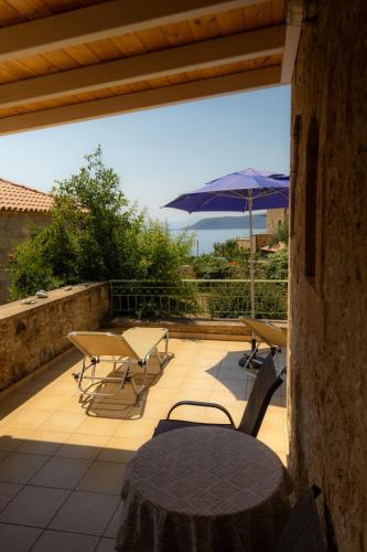 a patio with a table and chairs and an umbrella at Amoni Holiday Homes in Kardamili